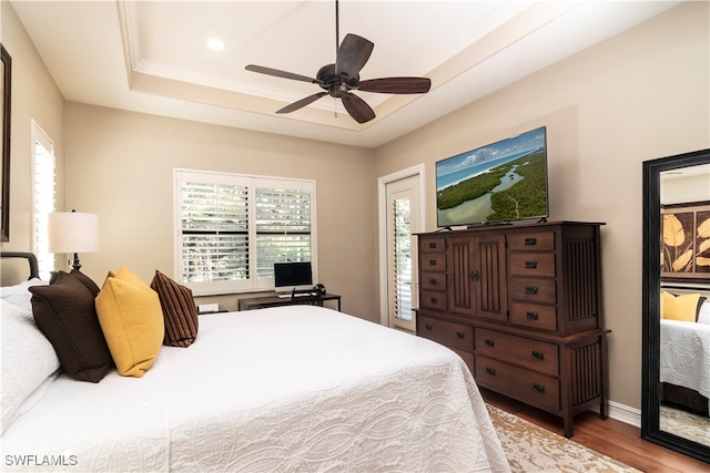 bedroom featuring wood-type flooring, a raised ceiling, and ceiling fan