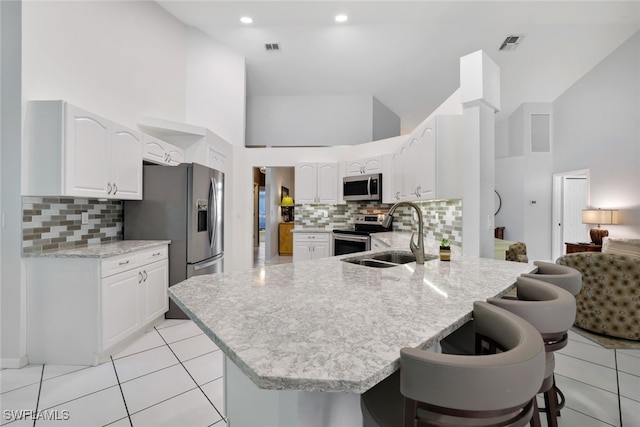 kitchen with kitchen peninsula, appliances with stainless steel finishes, sink, high vaulted ceiling, and white cabinets