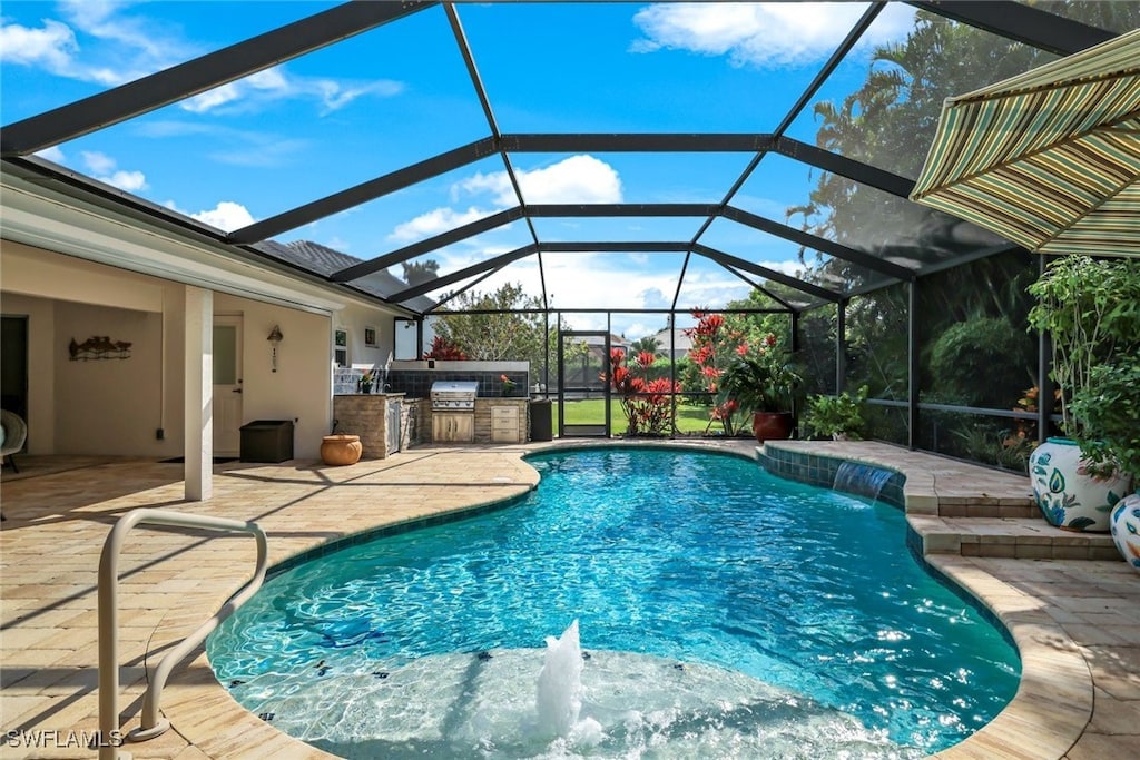 view of swimming pool with pool water feature, glass enclosure, a patio, and exterior kitchen