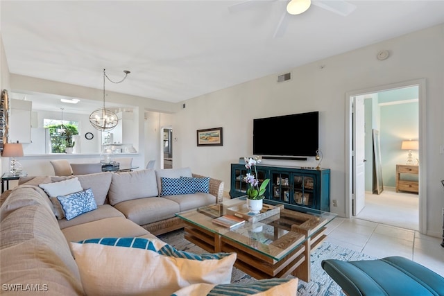 tiled living room featuring ceiling fan with notable chandelier