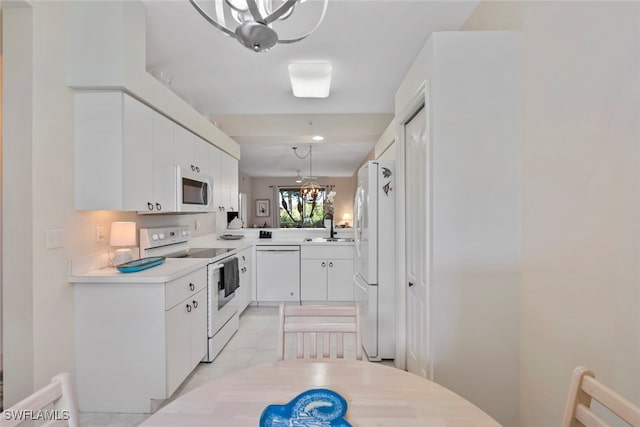 kitchen with pendant lighting, white appliances, an inviting chandelier, sink, and white cabinetry