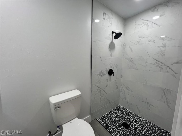 bathroom featuring a tile shower and toilet