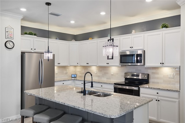 kitchen with decorative light fixtures, sink, appliances with stainless steel finishes, and a kitchen island with sink