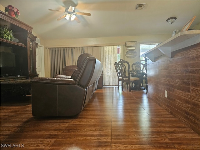 living room featuring wood walls, vaulted ceiling, ceiling fan, and dark hardwood / wood-style flooring