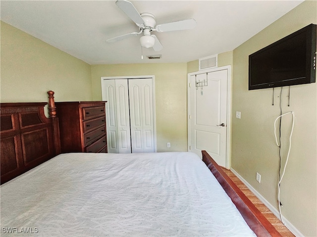 bedroom featuring multiple closets, wood-type flooring, and ceiling fan