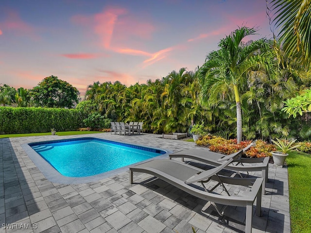 pool at dusk with a patio area