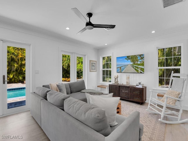 living room with ornamental molding, light wood-type flooring, and ceiling fan