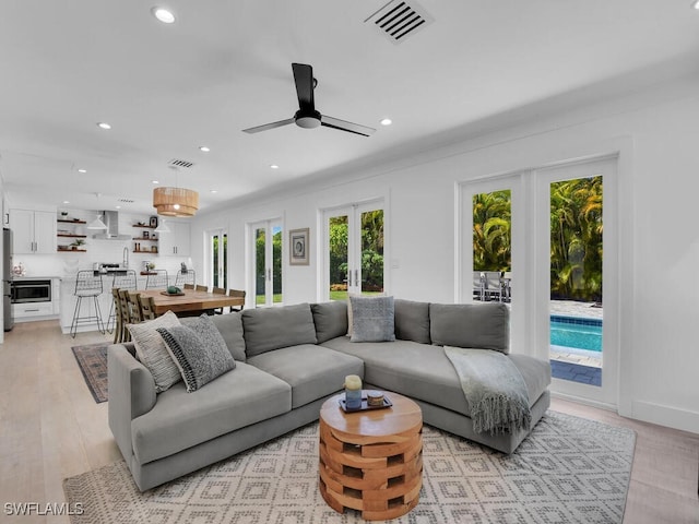 living room featuring french doors, ceiling fan, and light wood-type flooring