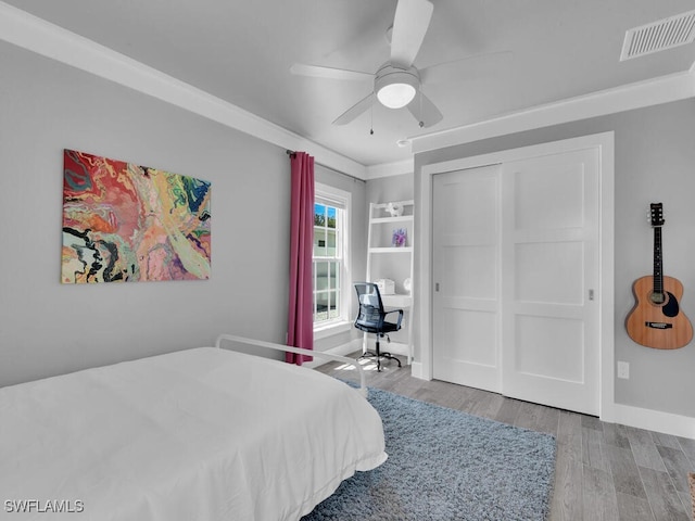 bedroom featuring ceiling fan, ornamental molding, hardwood / wood-style floors, and a closet