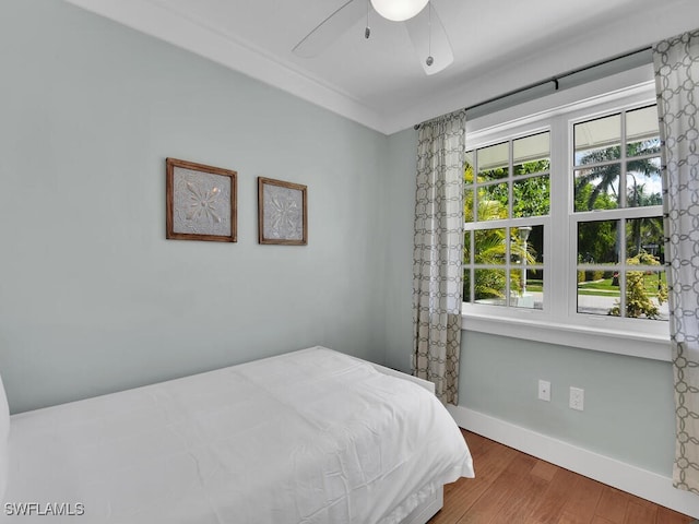 bedroom with crown molding, hardwood / wood-style floors, and ceiling fan