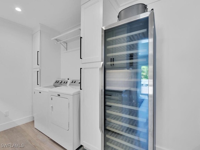 laundry room with washer and dryer, beverage cooler, and light hardwood / wood-style flooring