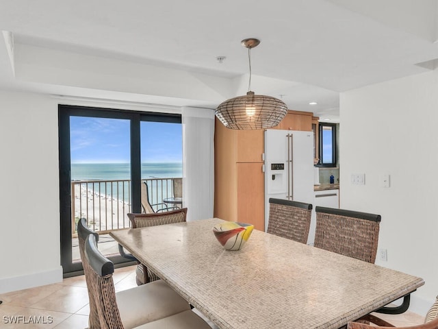 dining space featuring a beach view, light tile patterned floors, and a water view