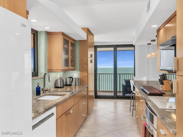 kitchen featuring wall oven, sink, pendant lighting, stone counters, and dishwasher