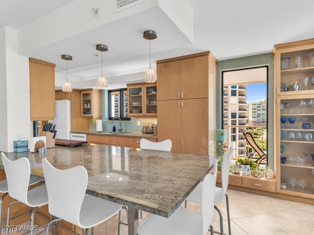 kitchen with a kitchen breakfast bar, kitchen peninsula, a raised ceiling, and pendant lighting