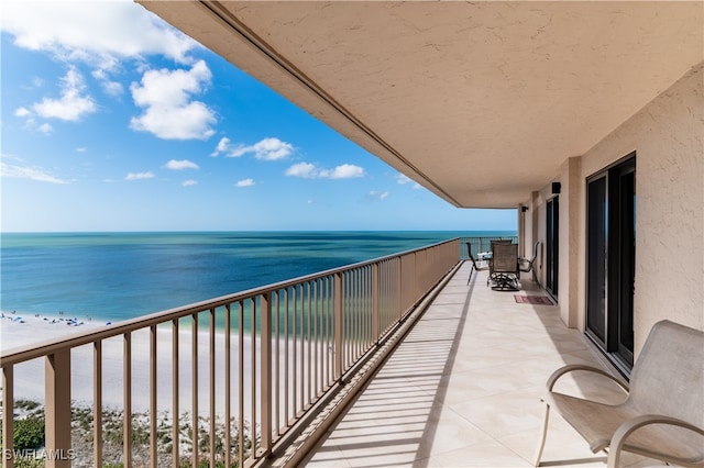 balcony with a water view and a view of the beach