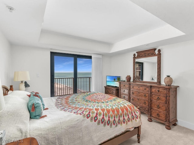 bedroom featuring a raised ceiling, light colored carpet, and access to outside