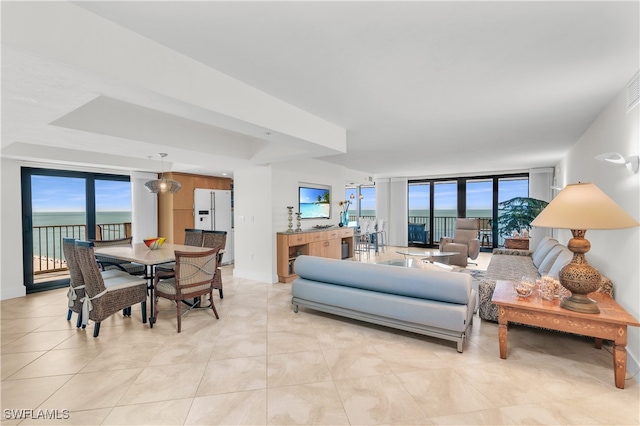 living room with a water view, light tile patterned flooring, and a wall of windows