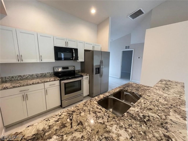 kitchen featuring high vaulted ceiling, sink, appliances with stainless steel finishes, stone countertops, and white cabinetry