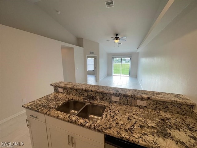 kitchen featuring white cabinets, sink, vaulted ceiling, ceiling fan, and dark stone countertops