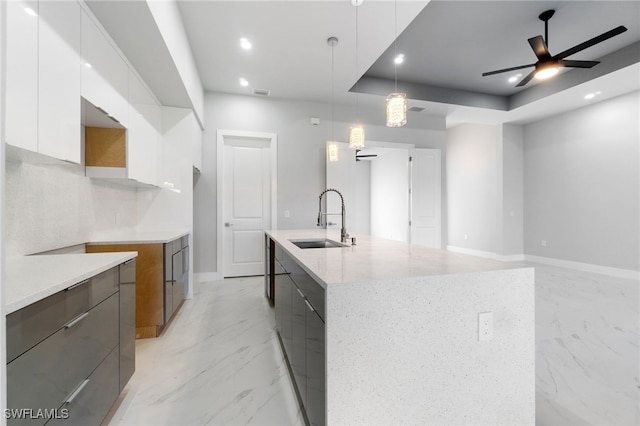 kitchen featuring sink, decorative light fixtures, ceiling fan, a large island, and white cabinetry