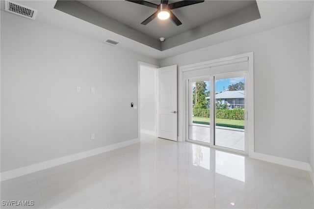 empty room featuring a raised ceiling and ceiling fan