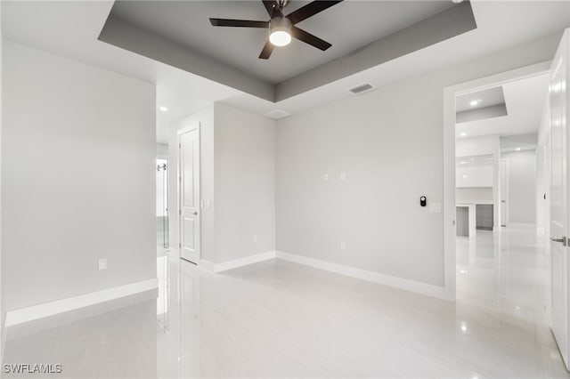 unfurnished room featuring a raised ceiling and ceiling fan