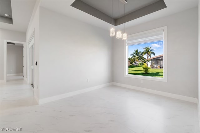 spare room featuring a raised ceiling and an inviting chandelier