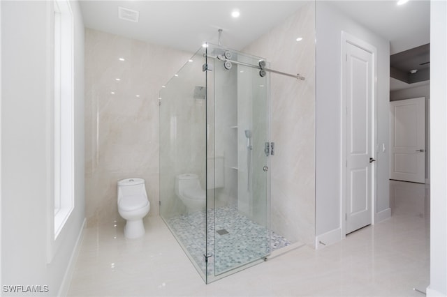 bathroom featuring tile patterned floors, toilet, walk in shower, and tile walls