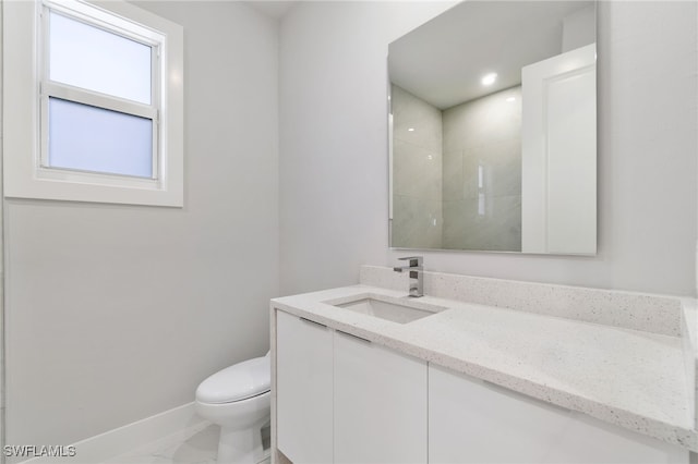 bathroom with tiled shower, vanity, and toilet