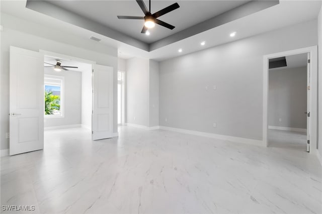 spare room with ceiling fan and a raised ceiling