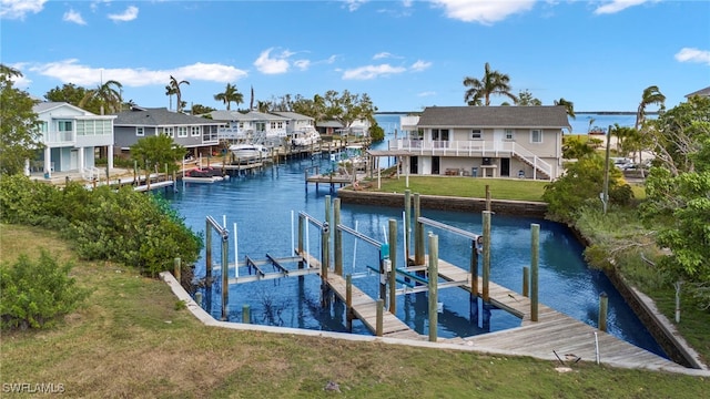 view of dock featuring a lawn, a water view, boat lift, and a residential view