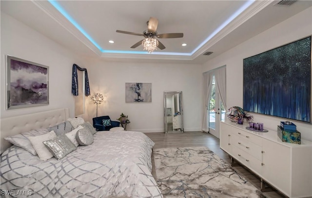 bedroom featuring a tray ceiling, visible vents, recessed lighting, and wood finished floors