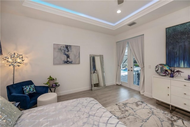 bedroom with visible vents, crown molding, wood finished floors, a raised ceiling, and access to outside