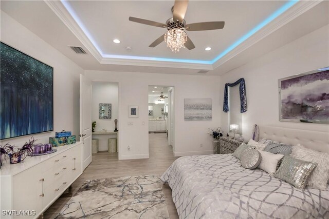 bedroom with light wood-type flooring, a tray ceiling, and ornamental molding