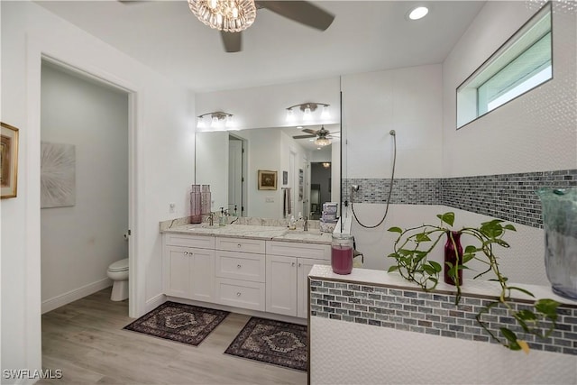 full bath with toilet, a sink, wood finished floors, a ceiling fan, and double vanity