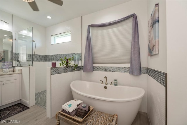 full bathroom featuring a freestanding bath, tile walls, vanity, and a walk in shower