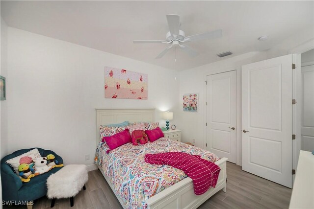 bedroom with ceiling fan, wood finished floors, and visible vents