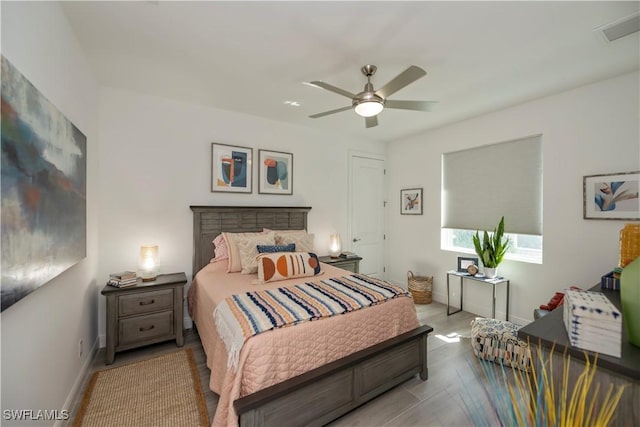 bedroom with a ceiling fan, baseboards, visible vents, and wood finished floors