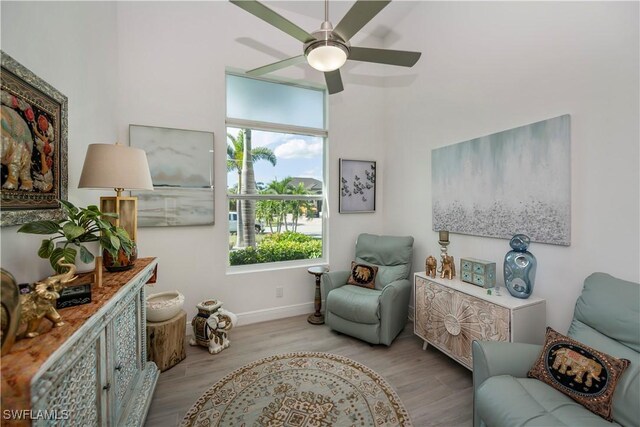 sitting room with ceiling fan, baseboards, and wood finished floors