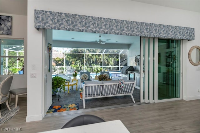 doorway to outside with a sunroom, baseboards, a ceiling fan, and wood finished floors