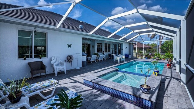 view of pool featuring glass enclosure and a pool with connected hot tub