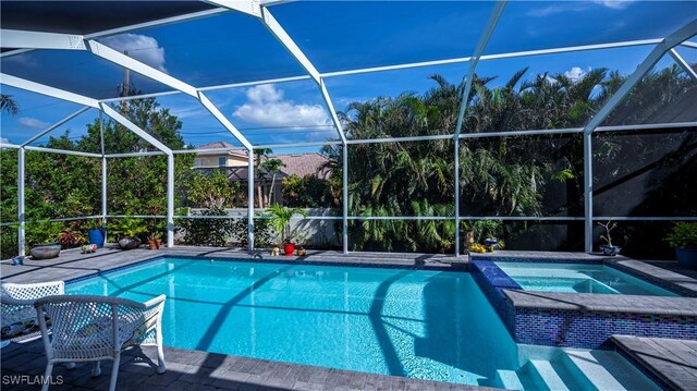 view of swimming pool with a lanai, a pool with connected hot tub, and a patio