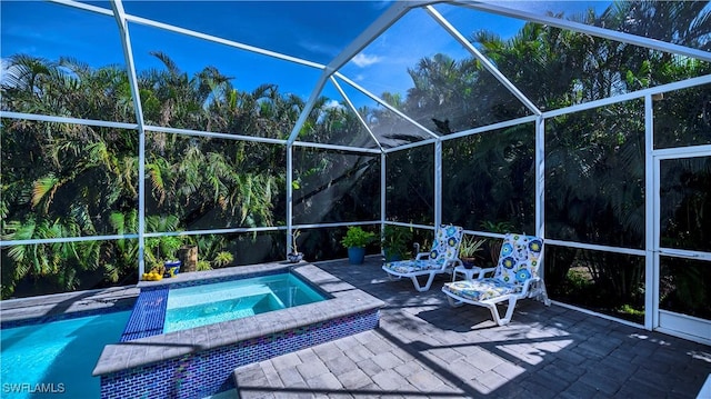 outdoor pool with glass enclosure, an in ground hot tub, and a patio area