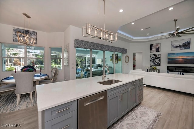 kitchen featuring a sink, dishwasher, open floor plan, and gray cabinetry