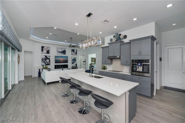 kitchen with visible vents, oven, black electric cooktop, gray cabinetry, and a sink