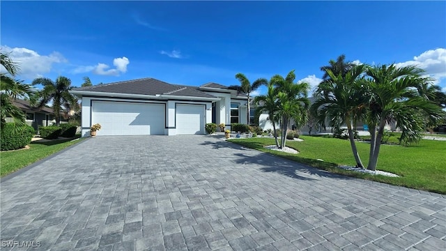 view of front of property featuring stucco siding, a front lawn, a garage, a tiled roof, and decorative driveway