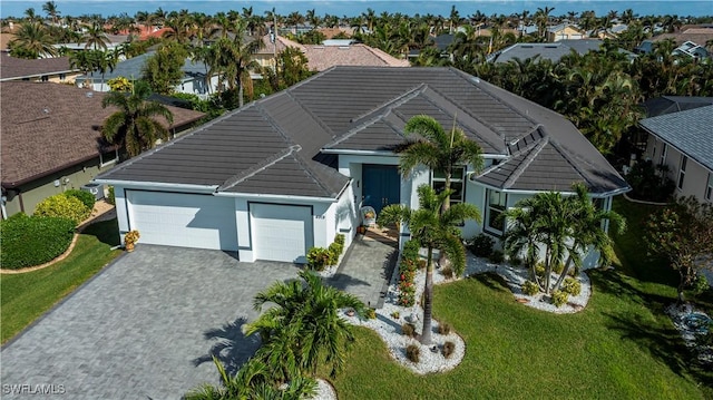 view of front of property with a garage, decorative driveway, a tile roof, and a residential view