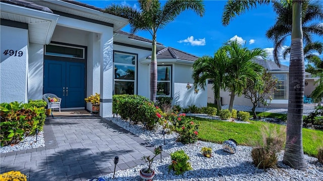 entrance to property with a tile roof and stucco siding