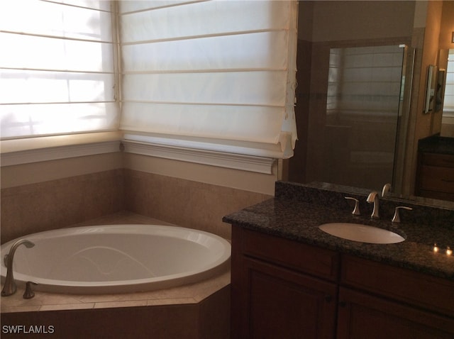 bathroom with vanity and tiled bath