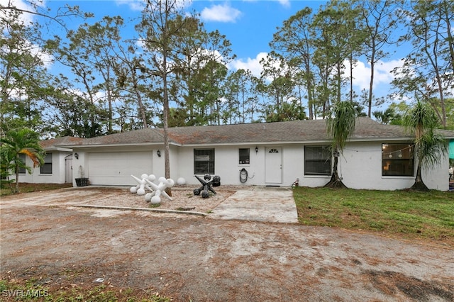 view of front facade featuring driveway, an attached garage, stucco siding, and a front lawn